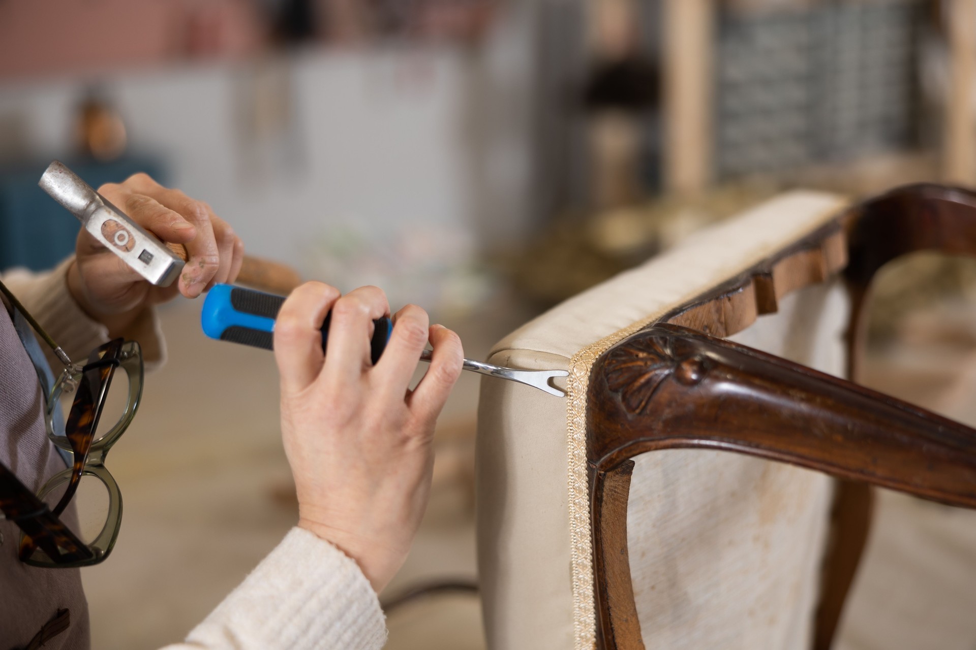 close up of  hands of  restorer reupholstering  antique wooden chair with cabriole legs